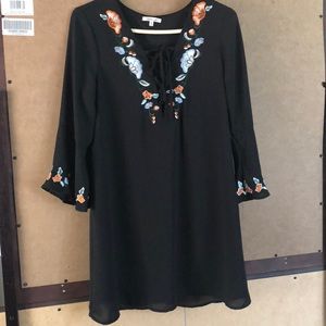 Medium length black dress with floral designs.